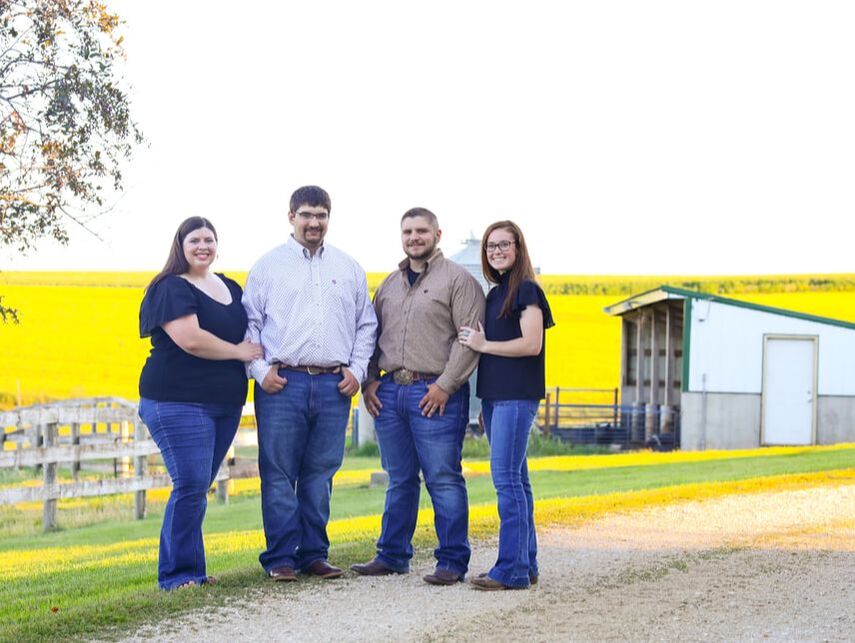 Four people standing in front of pig barns